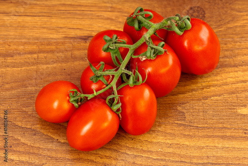 A bunch of red cherry tomatoes on a brown wooden table
