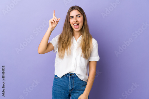 Young woman over isolated purple background intending to realizes the solution while lifting a finger up