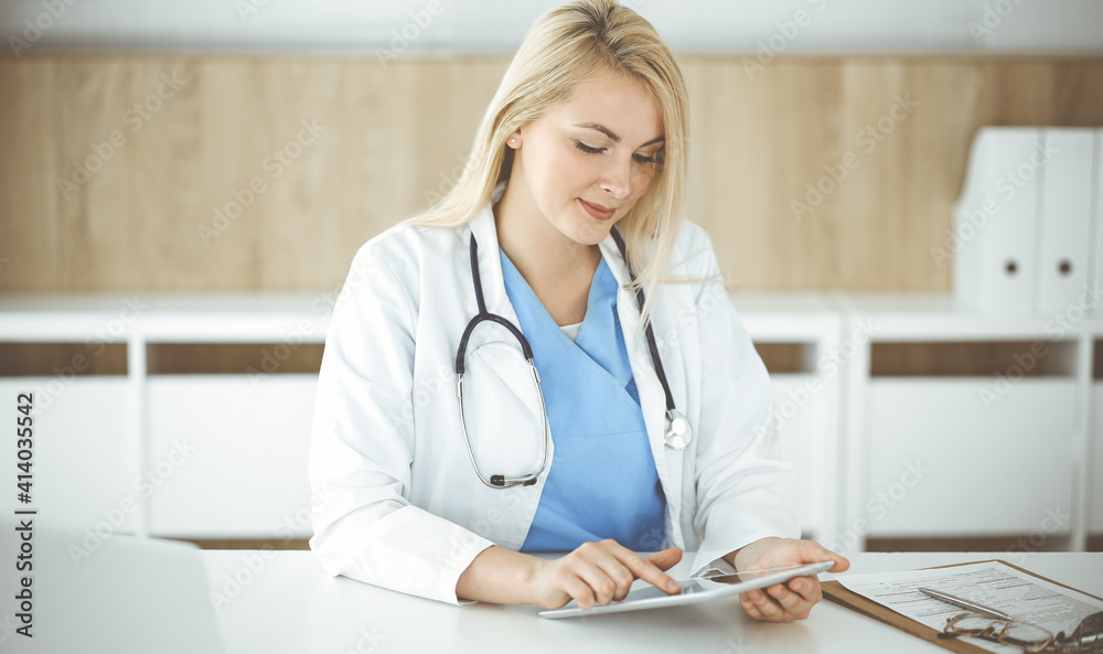 Woman-doctor standing in hospital or clinic and using tablet pc. Data and best service in medicine and healthcare Woman-doctor standing in hospital or clinic and using tablet pc. Data and best service in medicine and healthcare
