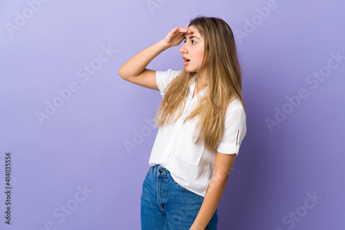 Young woman over isolated purple background with surprise expression while looking side