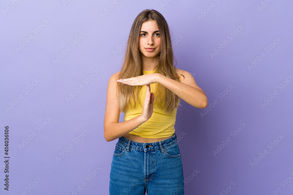 Young woman over isolated purple background making time out gesture