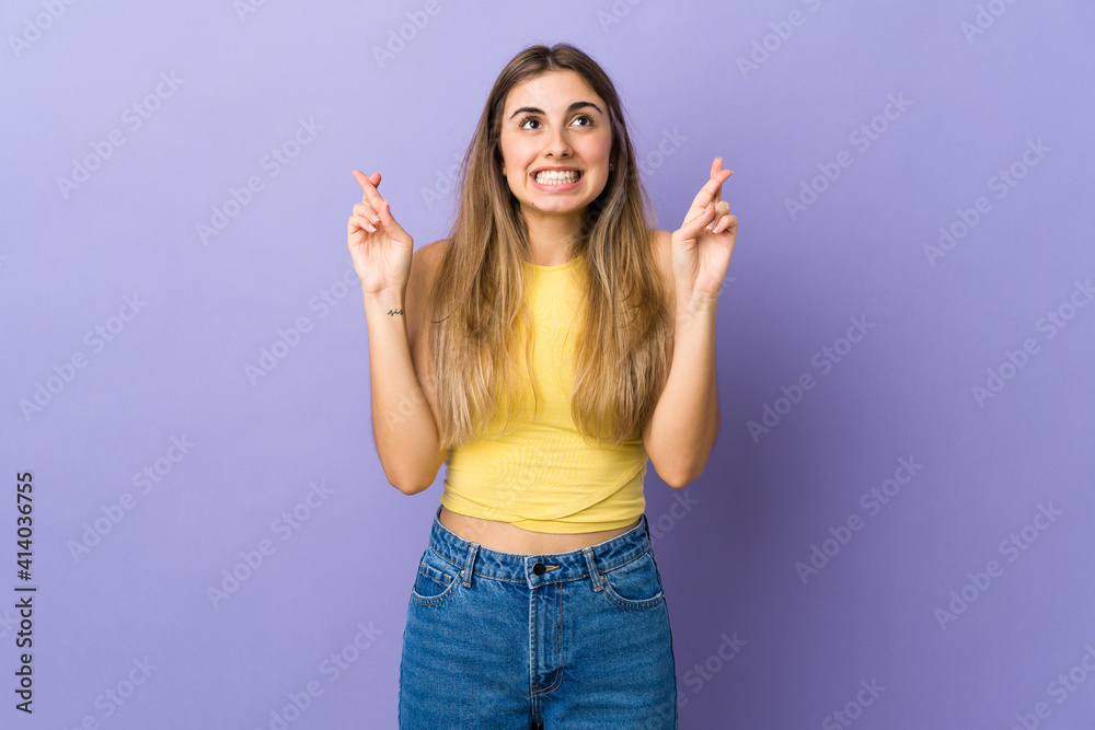 Young woman over isolated purple background with fingers crossing and wishing the best Young woman over isolated purple background with fingers crossing and wishing the best