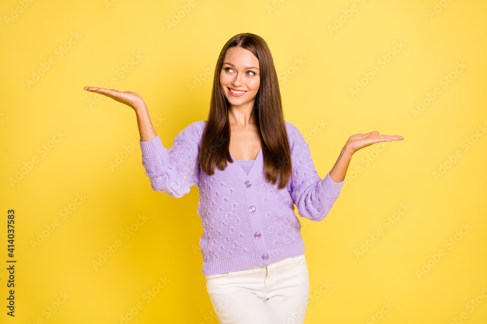 Portrait of pretty cheerful girl holding on palms two variants copy space deciding isolated over bright yellow color background Portrait of pretty cheerful girl holding on palms two variants copy space deciding isolated over bright yellow color background