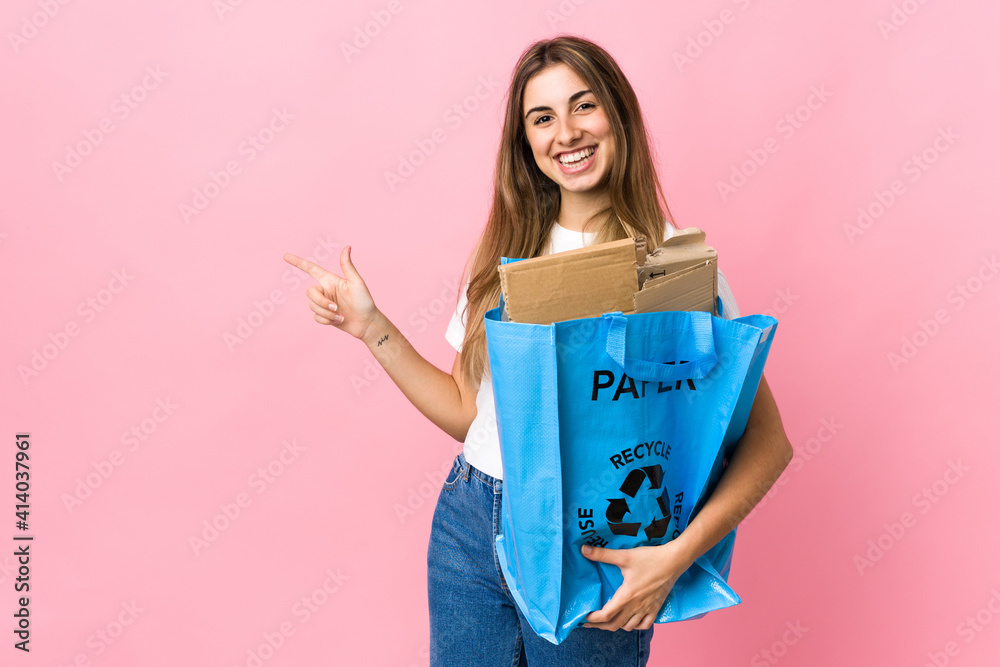 holding a recycling bag full of paper to recycle over isolated pink pointing finger to the side holding a recycling bag full of paper to recycle over isolated pink pointing finger to the side