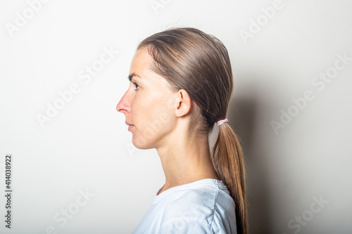 Girl in profile with protruding ears, on a light background.