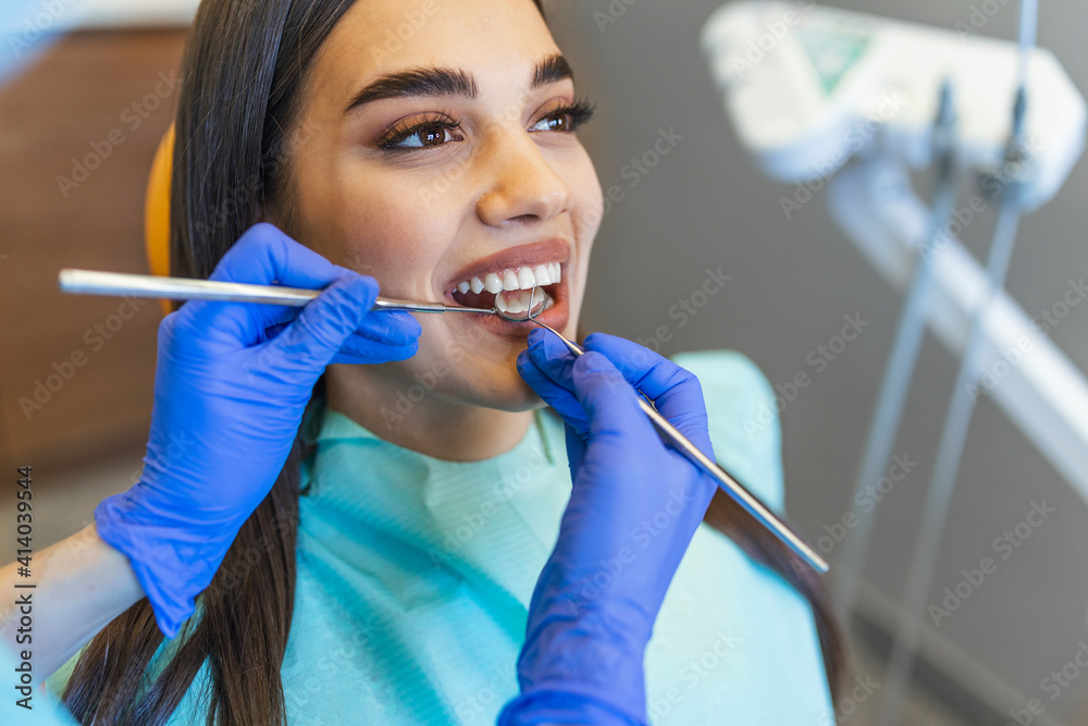 Woman looks in the mirror in dentist chair. Patient's teeth shade with