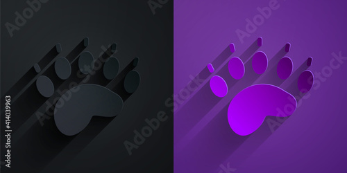 Paper cut Bear paw footprint icon isolated on black on purple background. Paper art style. Vector.