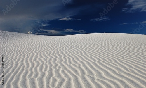 White sand waves against blue sky with clouds