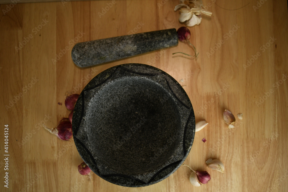 garlic and red onions on a wooden with black stone 
mortar background