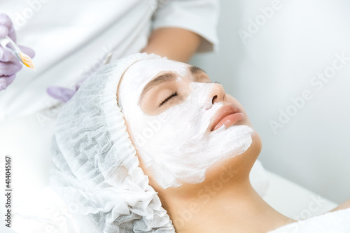 Facial skin care and protection. A young woman at a beautician's appointment. Portrait of a woman with a rejuvenating face mask