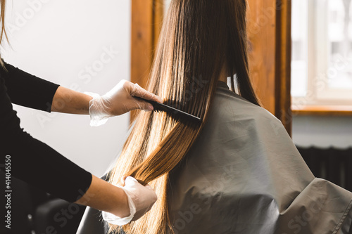Master hairdresser combs the girl's hair after washing and before styling in a beauty salon. Close up