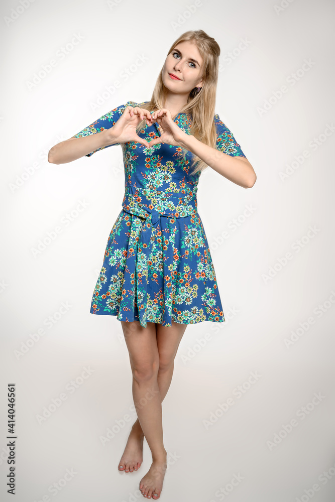 Naklejka premium Young girl in a summer dress with a heart out of her hands