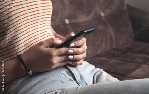 Woman using mobile phone while sitting on a couch at home.