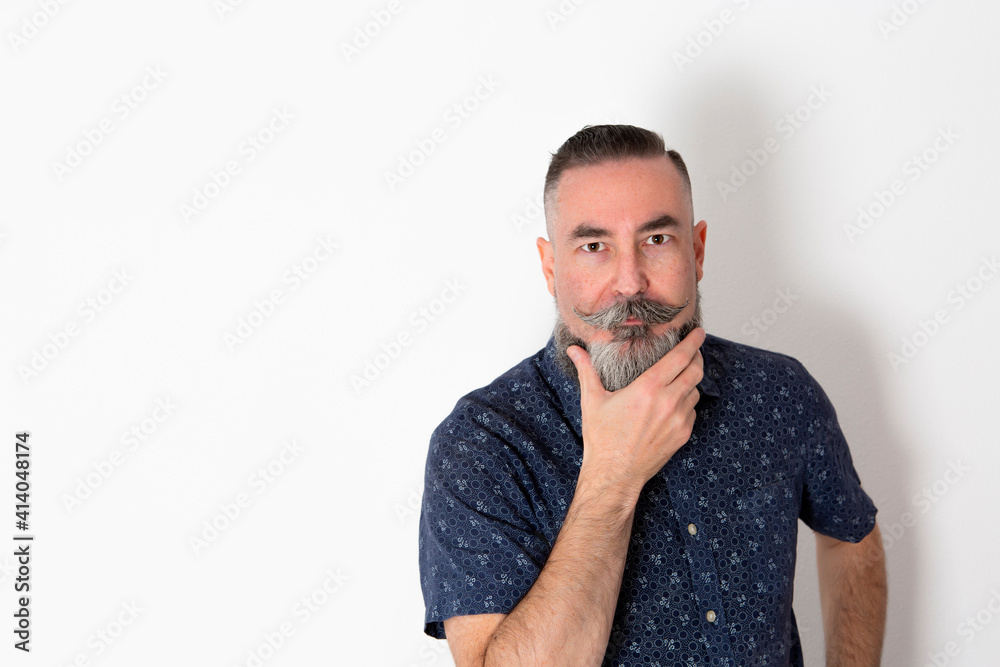 Caucasian bearded man 40-45 years old, on white background looking straight ahead with his hand fixing his gray beard. Caucasian bearded man 40-45 years old, on white background looking straight ahead with his hand fixing his gray beard.