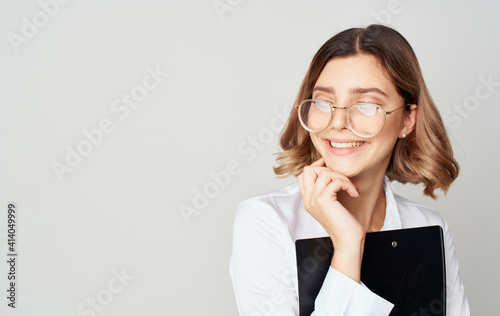 Business woman in a shirt and glasses on a light background with documents in hands