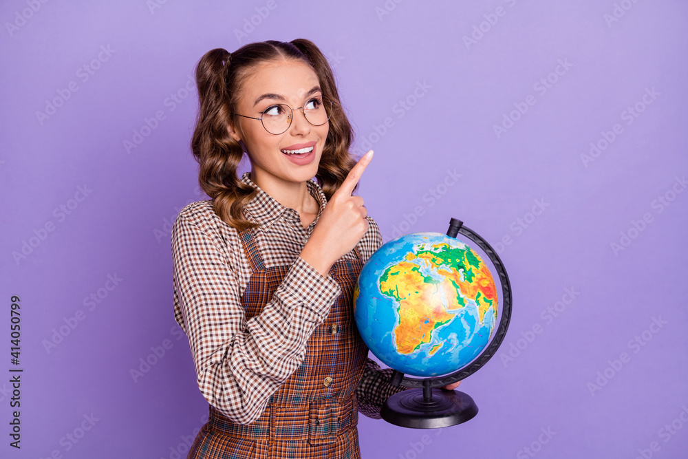 Photo of charming positive person look indicate finger empty space hold globe isolated on violet color background Photo of charming positive person look indicate finger empty space hold globe isolated on violet color background