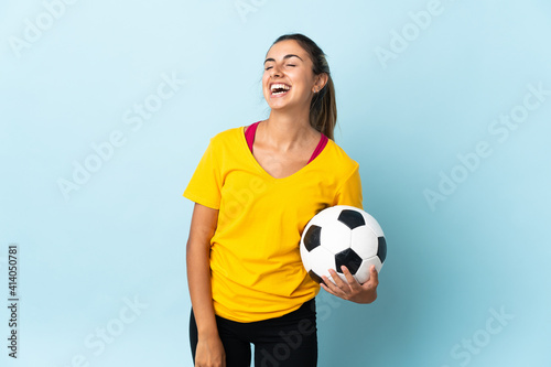 Young hispanic football player woman over isolated on blue background laughing © luismolinero
