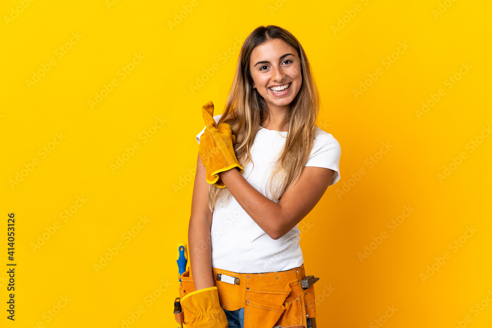 Young hispanic electrician woman over isolated yellow wall pointing to the side to present a product Young hispanic electrician woman over isolated yellow wall pointing to the side to present a product