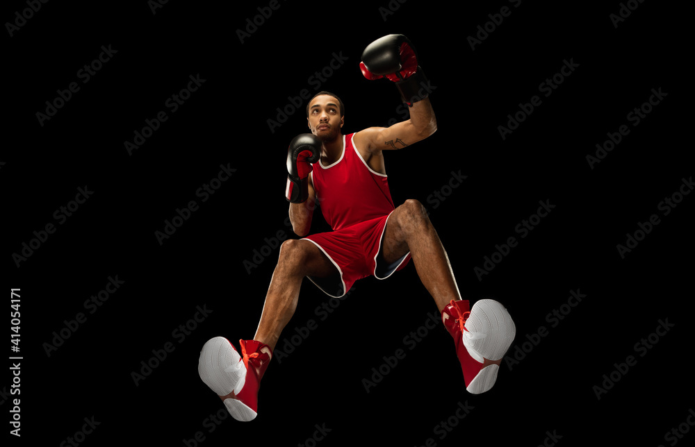 Young african-american professional boxer in action, motion isolated on black background, look from the bottom. Concept of sport, movement, energy and dynamic, healthy lifestyle. Training, practicing. Young african-american professional boxer in action, motion isolated on black background, look from the bottom. Concept of sport, movement, energy and dynamic, healthy lifestyle. Training, practicing.