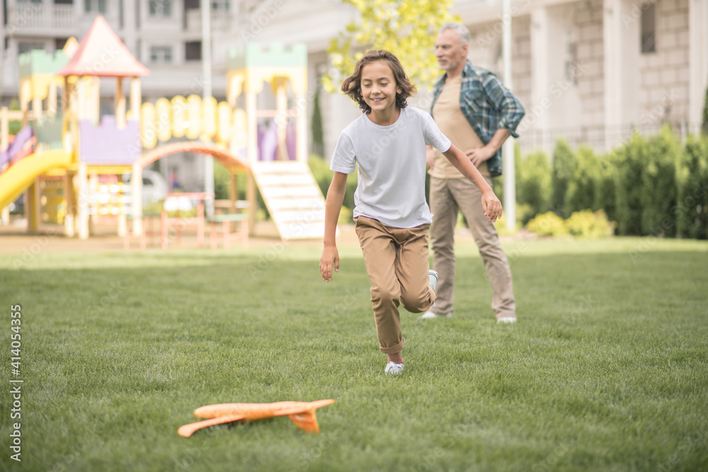 Cute dark-haired boy running after the toy plane