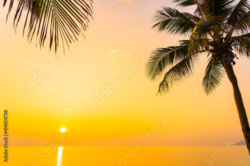 Coconut palm tree around sea beach ocean at sunset or sunrise
