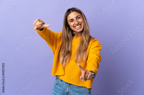 Young hispanic woman over isolated purple background pointing front with happy expression