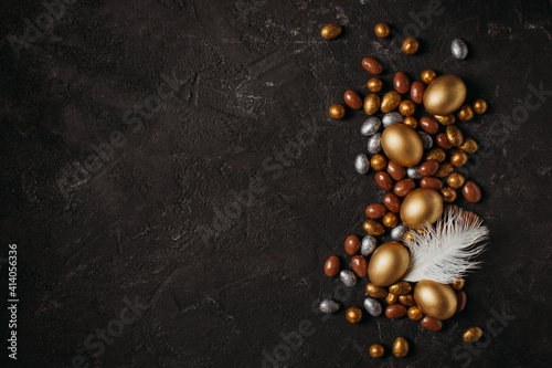 Easter concept card with golden eggs and candy sweet frame falt lay on black background photo