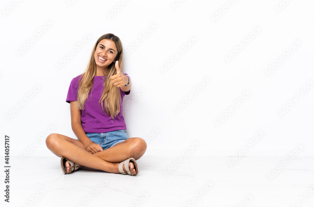 Young hispanic woman sitting on the floor with thumbs up because something good has happened