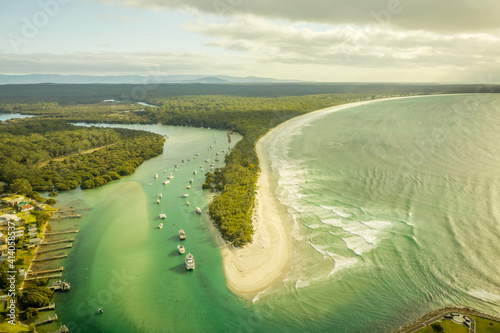 Aerial view of a small boats fleet sailing the Currambene creek at sunset, Huskisson, New South Wales, Australia. photo