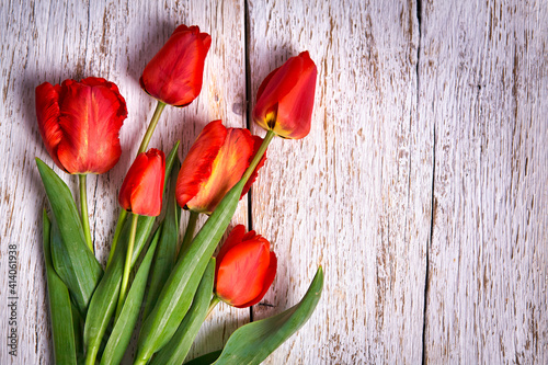 Red tulips bouquet over white wooden table background with copy space