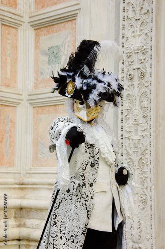 Fotografie Mask in  in traditional Venetian costume perfectly compatible with palazzo wall at background at traditional Carnival in Vemice, Italy