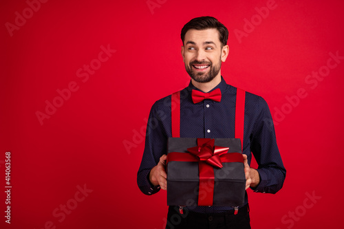 Photo of young happy cheerful good mood man look copyspace give you valentine day gift isolated on red color background © deagreez