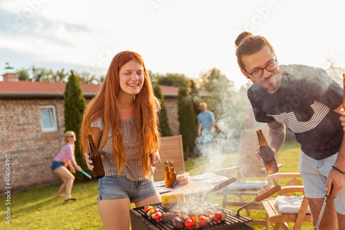 Friends havng fun drinking beer and grilling meat at backyard barbecue party photo