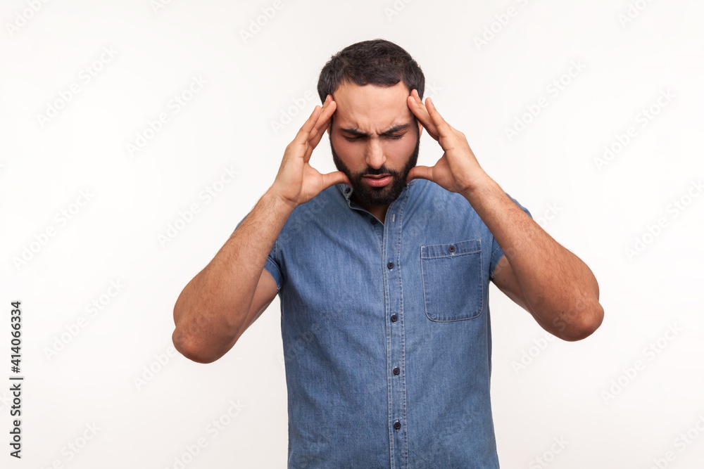 Fototapeta premium Unhappy frustrated bearded man massaging temples feeling headache, suffering migraine or high blood pressure, trying to concentrate. Indoor studio shot isolated on white background