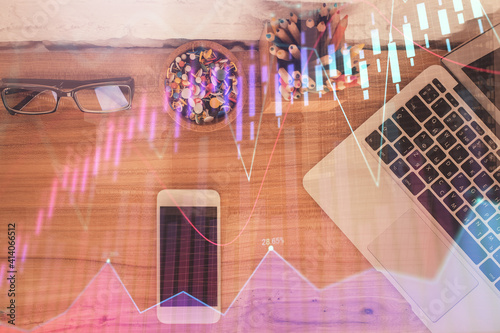 Double exposure of financial graph hologram over desktop with phone. Top view. Mobile trade platform concept. © peshkova