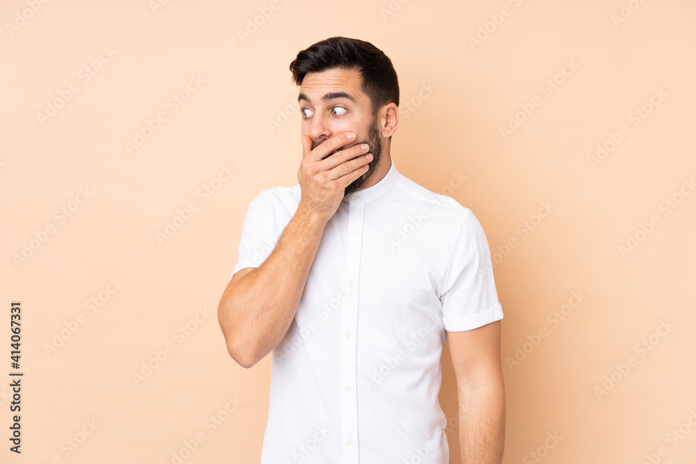 Caucasian handsome man isolated on beige background doing surprise gesture while looking to the side Caucasian handsome man isolated on beige background doing surprise gesture while looking to the side