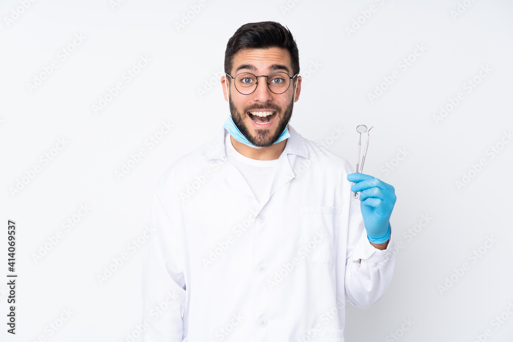 Dentist man holding tools isolated on white background with surprise facial expression Dentist man holding tools isolated on white background with surprise facial expression