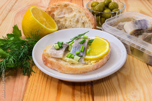 Open sandwich with pickled herring slices against ingredients  close-up