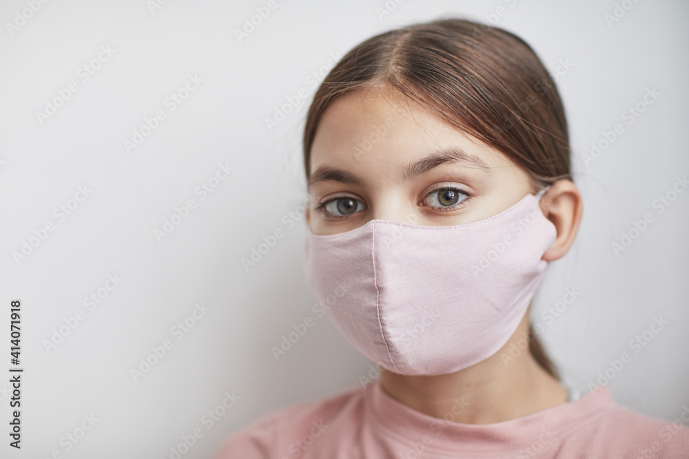 Close up portrait of cute girl wearing pink mask and looking at camera while standing against white background, copy space Close up portrait of cute girl wearing pink mask and looking at camera while standing against white background, copy space