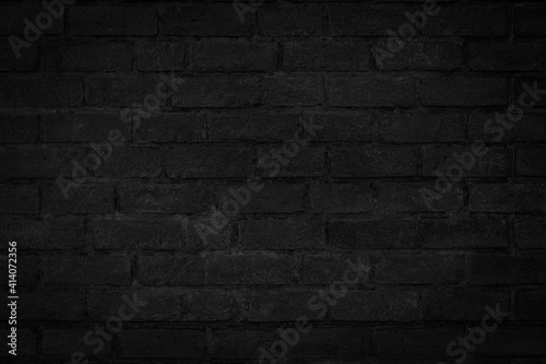Old vintage black color grunge brick wall textured background with vignette at the edge of picture and an empty space for text.