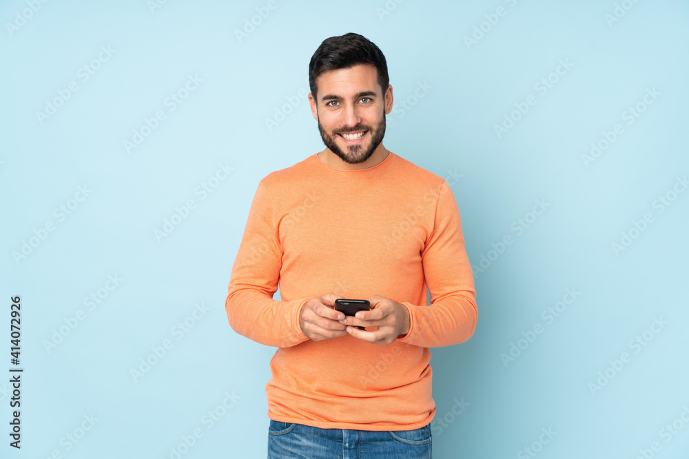 Caucasian handsome man sending a message with the mobile over isolated blue background Caucasian handsome man sending a message with the mobile over isolated blue background