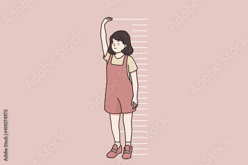 Children growing, height of body concept. Smiling little girl child cartoon character standing near wall measuring height with hands and stripes in pink wall vector illustration 
