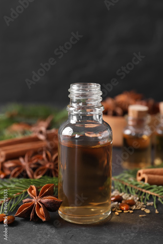 Fototapeta Naklejka Na Ścianę i Meble -  Bottle of essential oil, anise, cinnamon and fir tree branches on black table