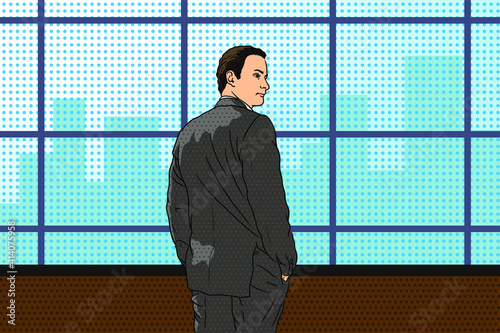 A young man in a businessman suit stands near the window and looks at the city.