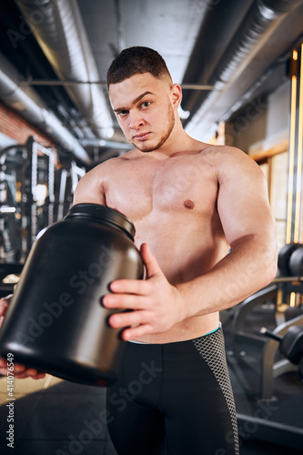 Young bodybuilder using sport nutrition during training