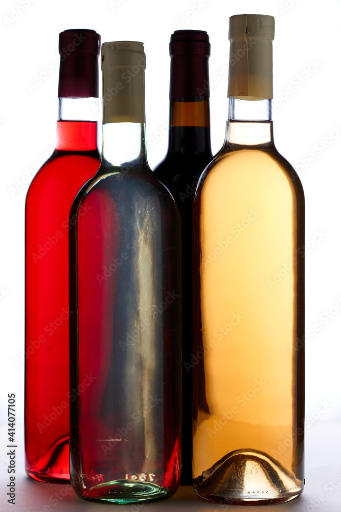 Four bottles of wine of different sorts on the white background. Wine bottles collection different colors isolated on white background, mock up Four bottles of wine of different sorts on the white background. Wine bottles collection different colors isolated on white background, mock up