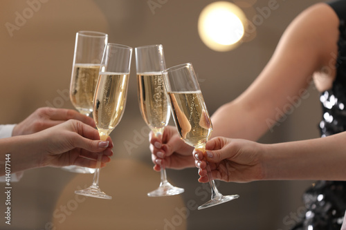 People clinking glasses of champagne against blurred background, closeup. Bokeh effect © New Africa