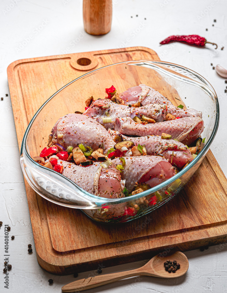 Raw chicken legs and lots of spice in a transparent dish on a white background. Raw chicken legs and lots of spice in a transparent dish on a white background.