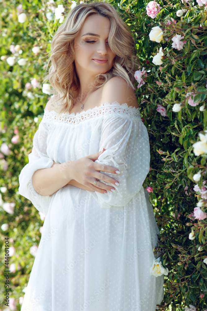 Smiling pregnant woman resting in the rose garden. Posing outdoors. Motherhood. High quality photo. Smiling pregnant woman resting in the rose garden. Posing outdoors. Motherhood. High quality photo.