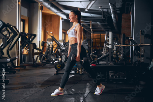 Cheerful young woman enjoying workout with weights